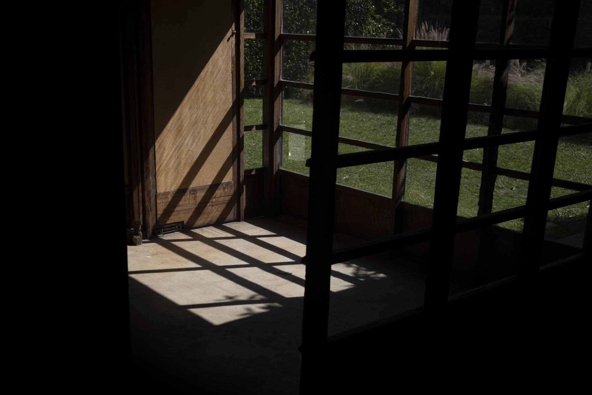 Late afternoon light falling through the gridded windows of the MAK Center, Los Angeles, onto a bare interior floor.